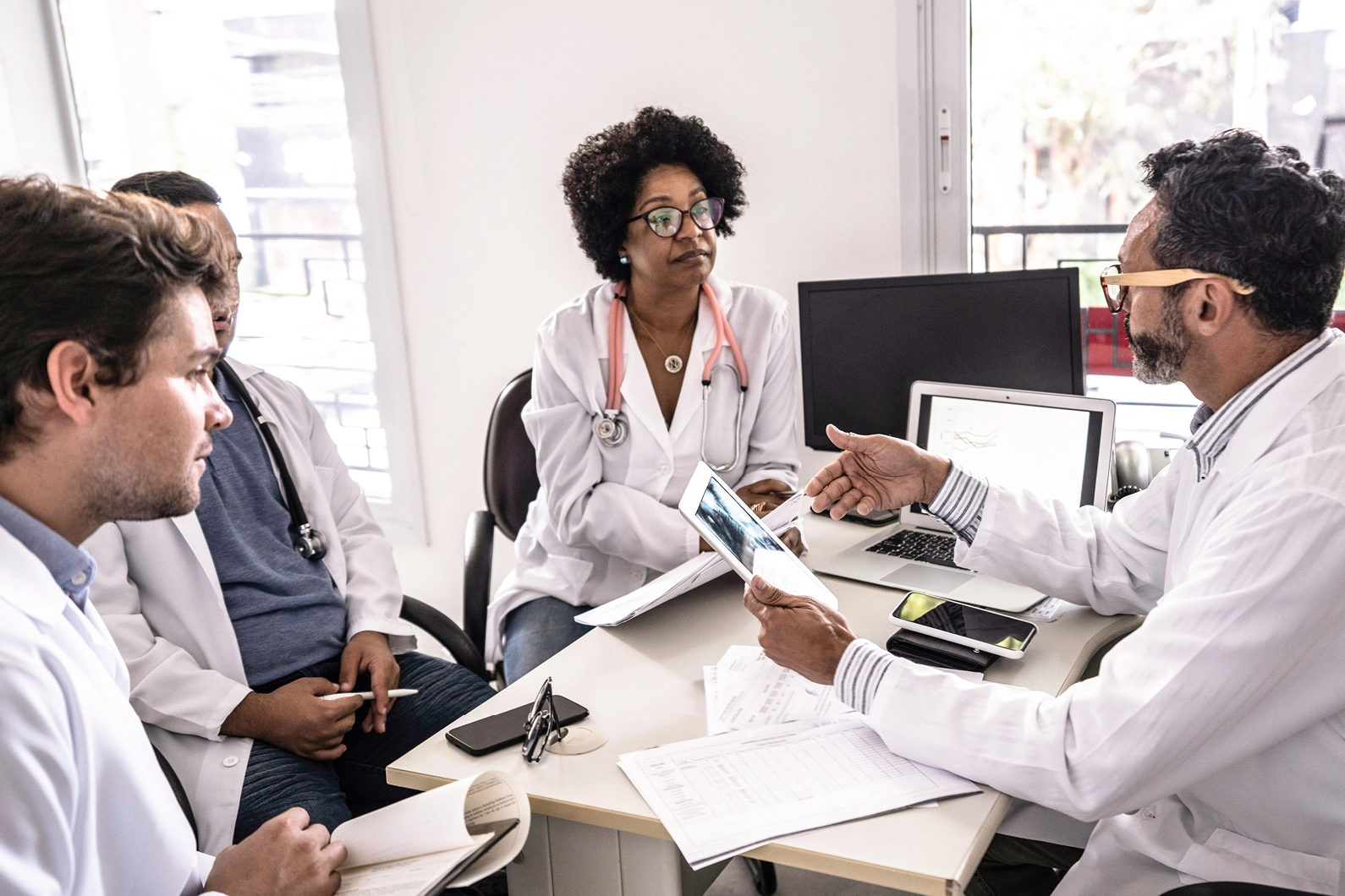 Four doctors gathered around a desk having a discussion
