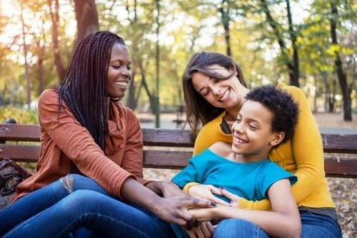 Two adults and a child laughing on a bench