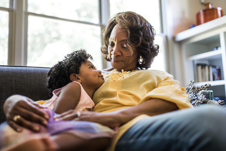 Grandmother and granddaughter cuddling on couch