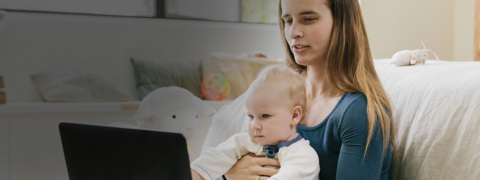 Woman with baby on laptop in living room