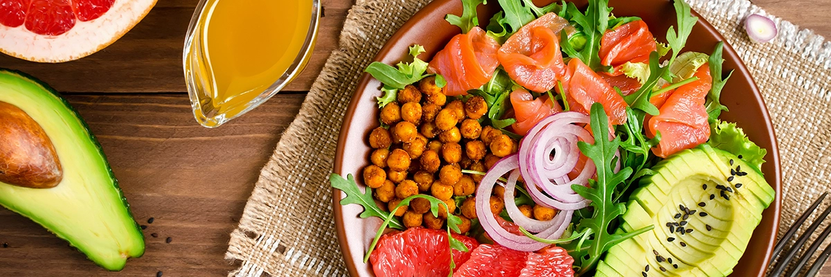 Healthy salad bowl with salmon, grapefruit, spicy chickpeas, avocado, red onion and arugula