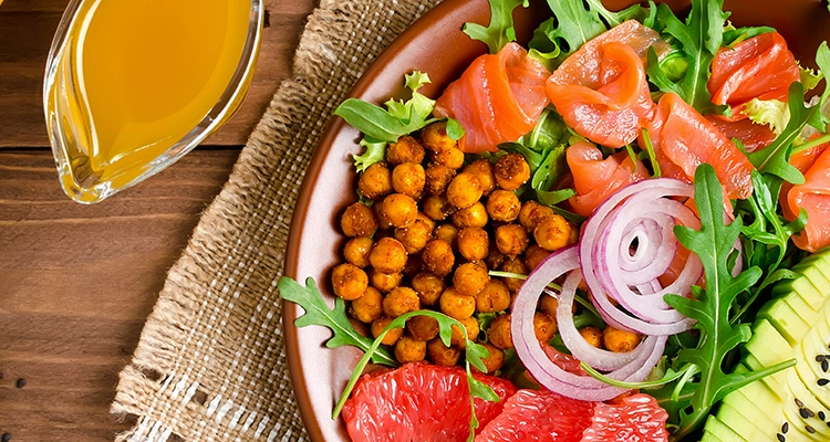 Healthy salad bowl with salmon, grapefruit, spicy chickpeas, avocado, red onion and arugula
