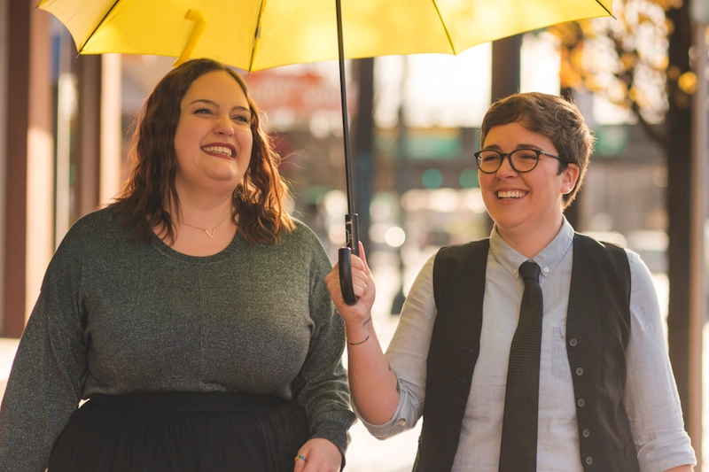 Two people walking under umbrella and smiling