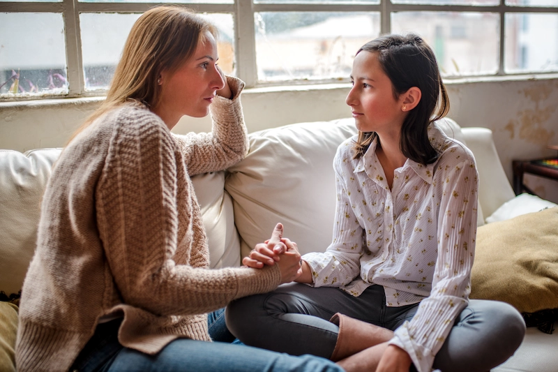 Parent with child on couch holding hands
