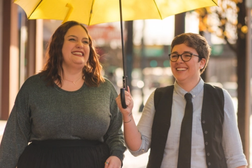 Two people walking under umbrella and smiling