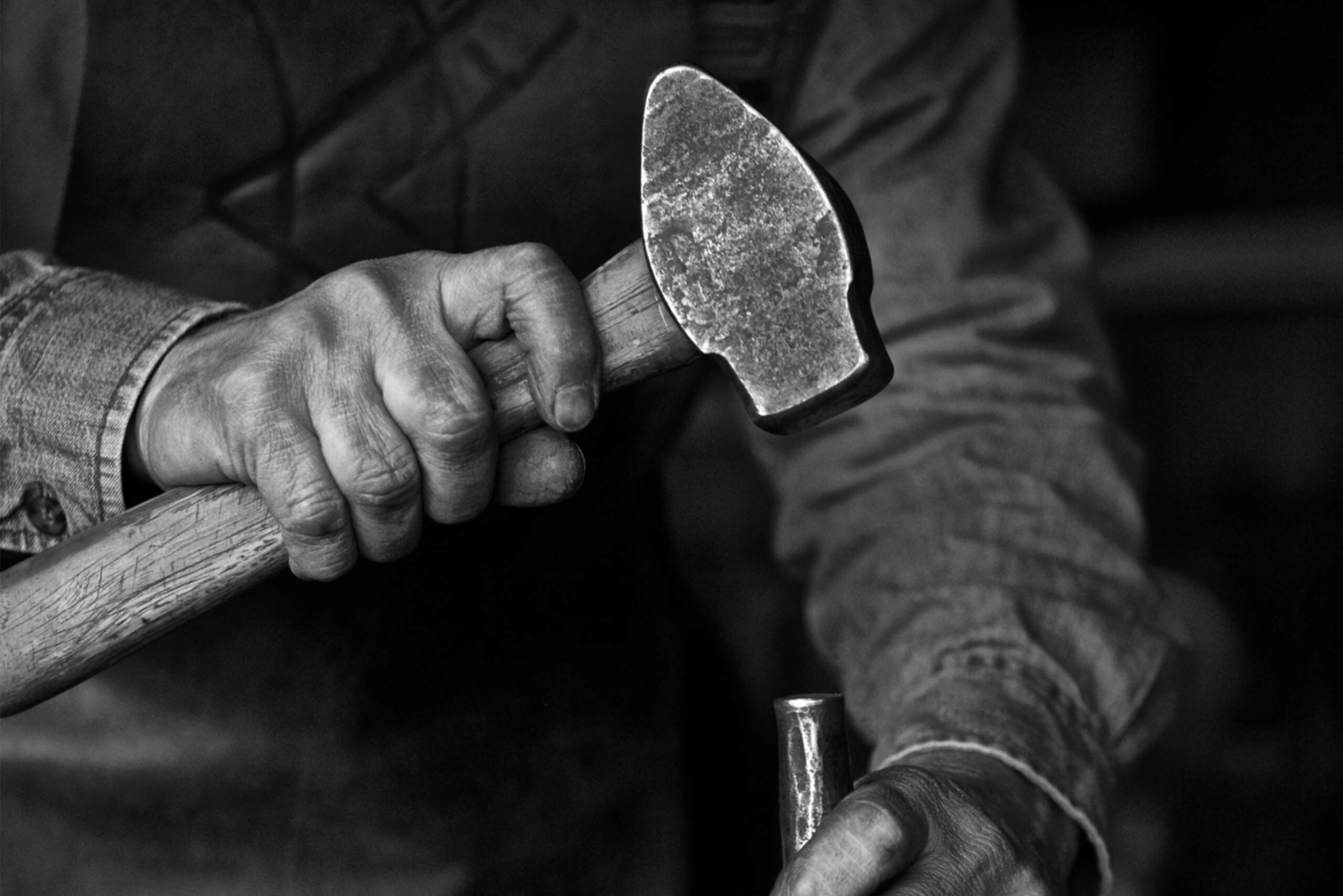 close up image of a hand with a hammer and nail