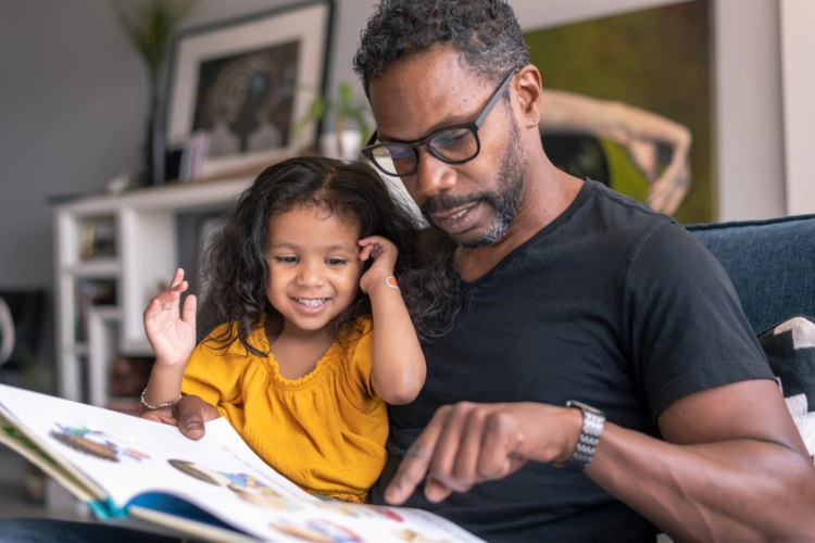 father and daughter reading on the couch