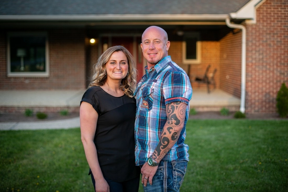picture of a couple standing in front of home