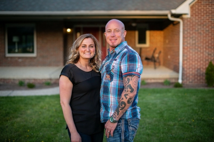 picture of a couple standing in front of home