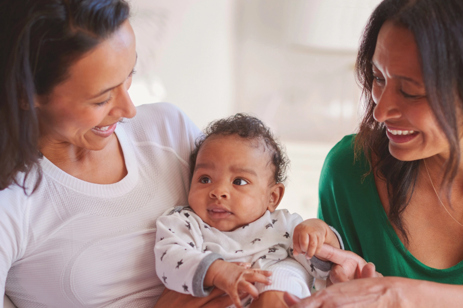 2 women smiling and holding a baby