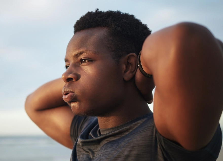 young male with hands behind his neck looking concerned
