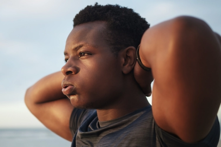 young male with hands behind his neck looking concerned