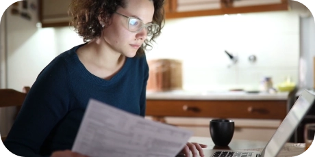 woman looking at medical bills and computer in her kitchen