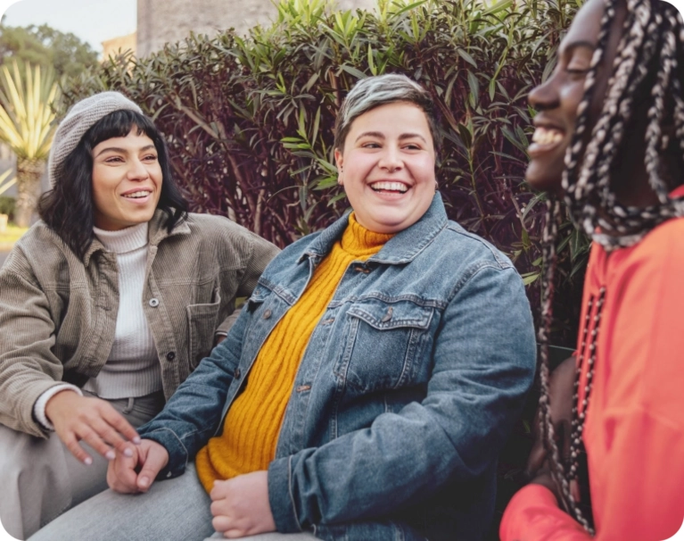 Three female laughing together on a bench