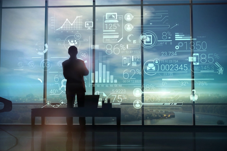GPT Claude blog post. Image is a silhouette of a man stands on the background of large office windows and views a hologram of corporate infographic with work data.