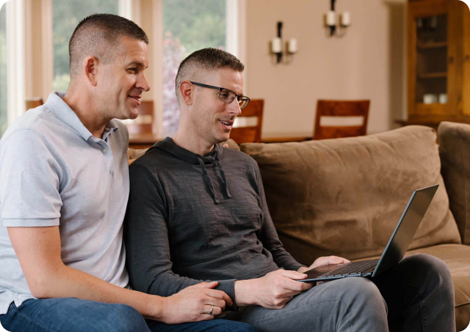 gay couple sitting in living room and speaking with a virtual medical provider.