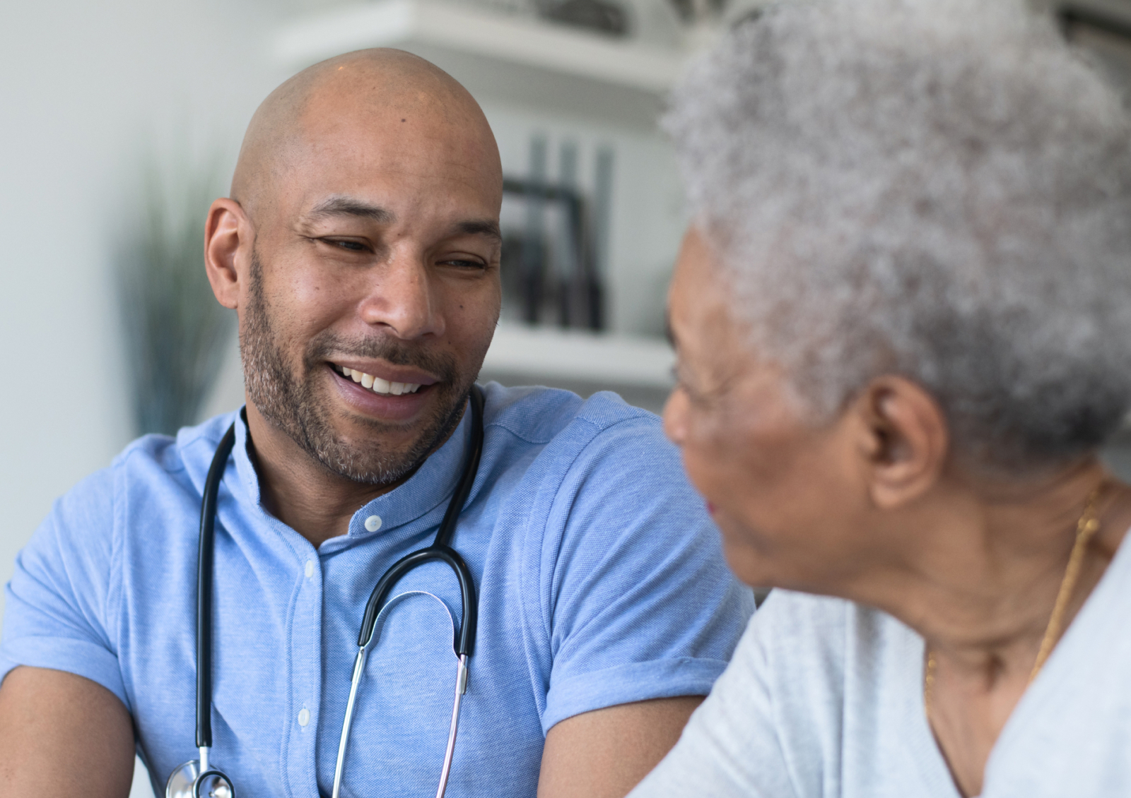 A doctor speaks with an elderly patient in his office