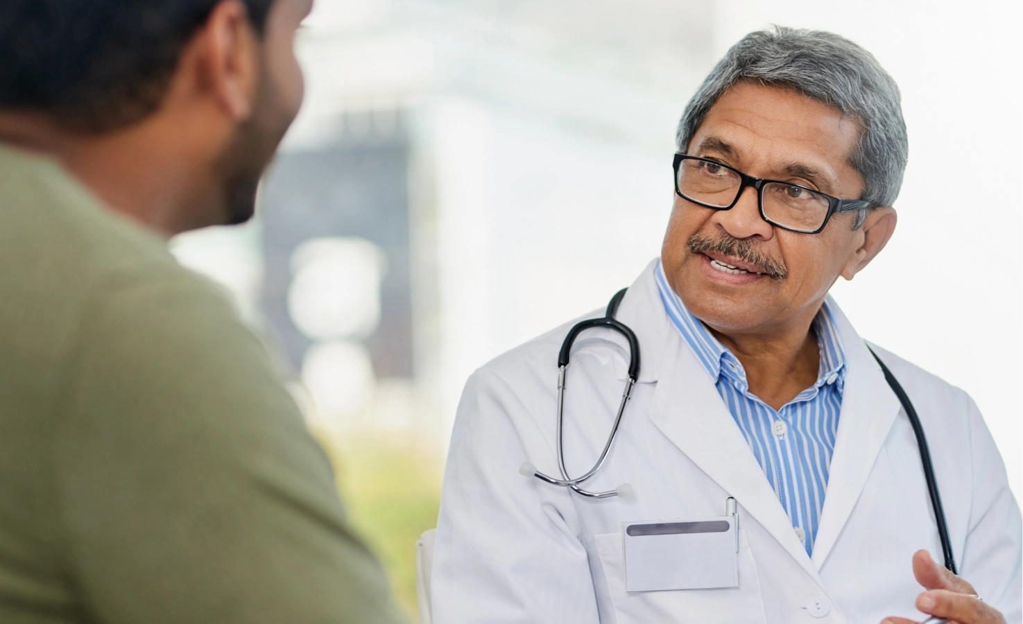 An in-person doctor chats with a patient in his office