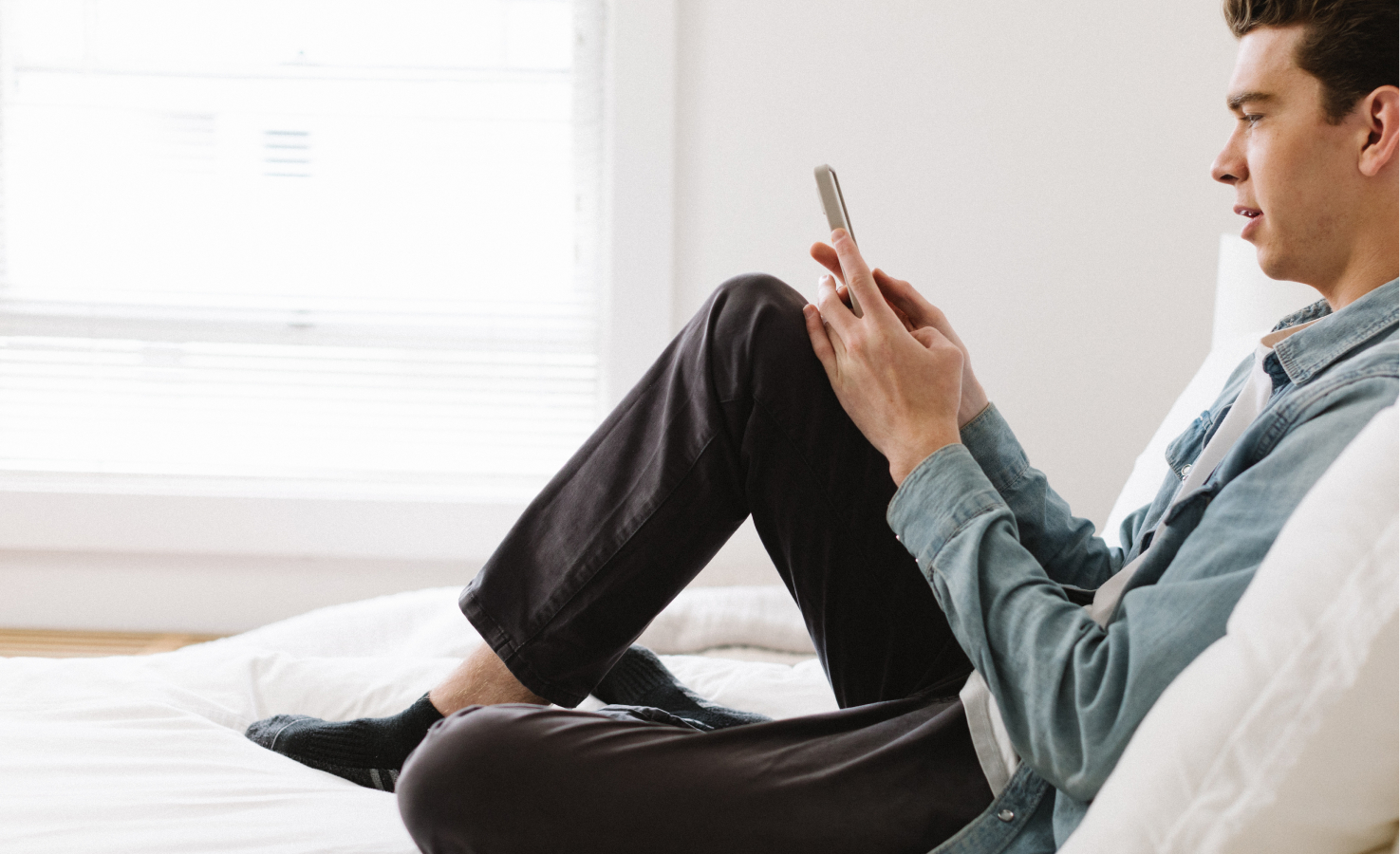 A young man sits at home and explores the Included Health app on his phone