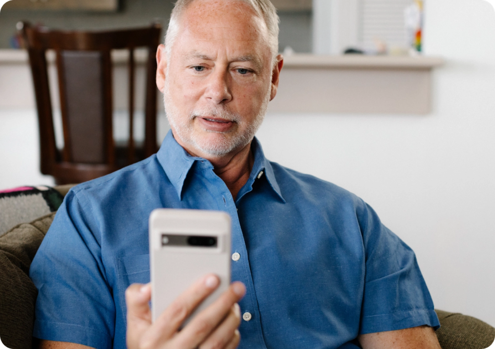 A older man holds us his phone to speak with a Care Coordinator