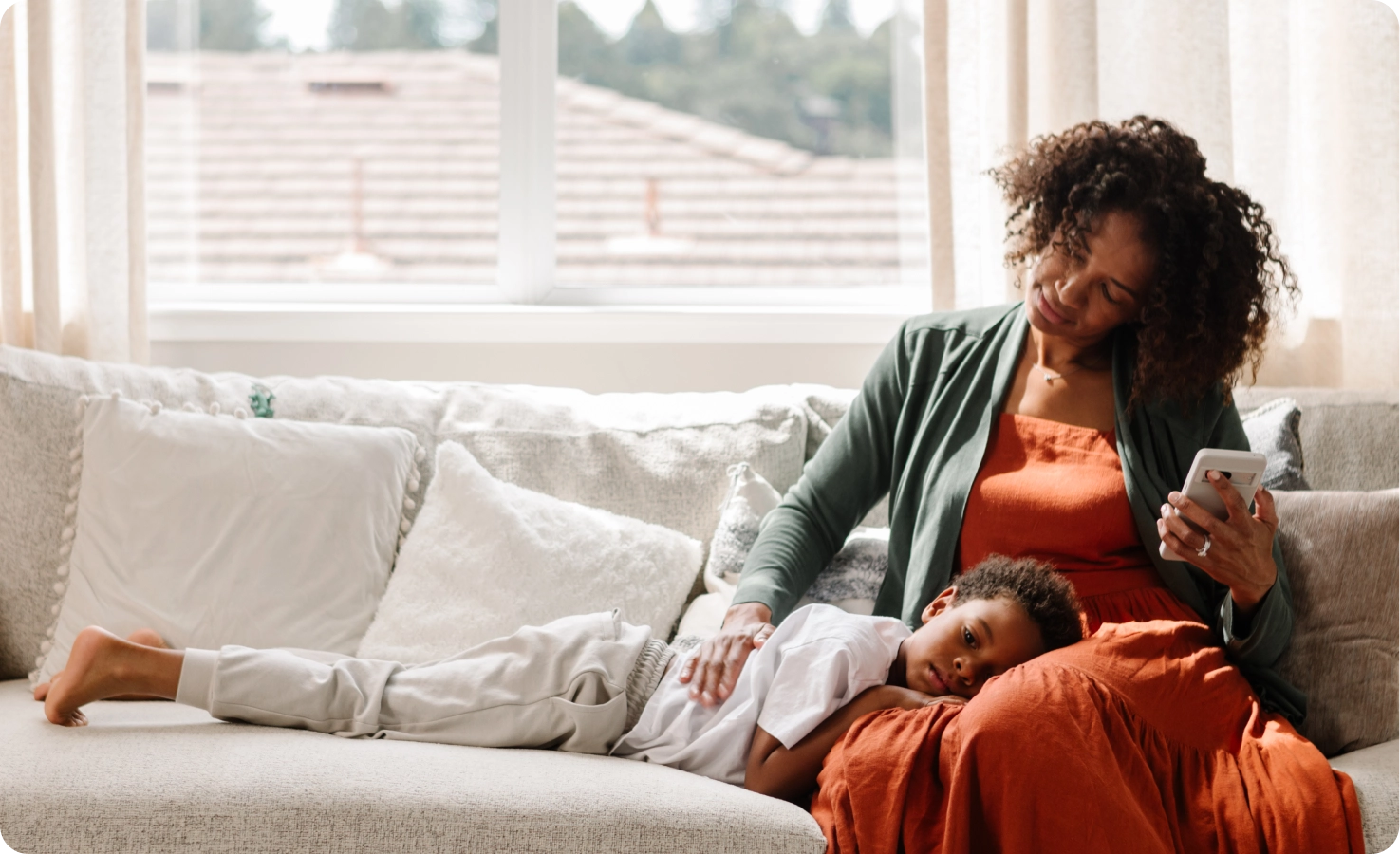 A black mother looks at her soon who has his head in her lap