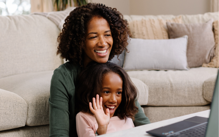 A young girl sits in her mom’s lap while they take a virtual visit