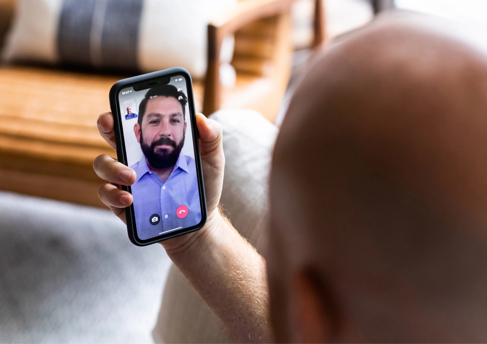 A man holds up a phone where he is taking a virtual visit with a therapist