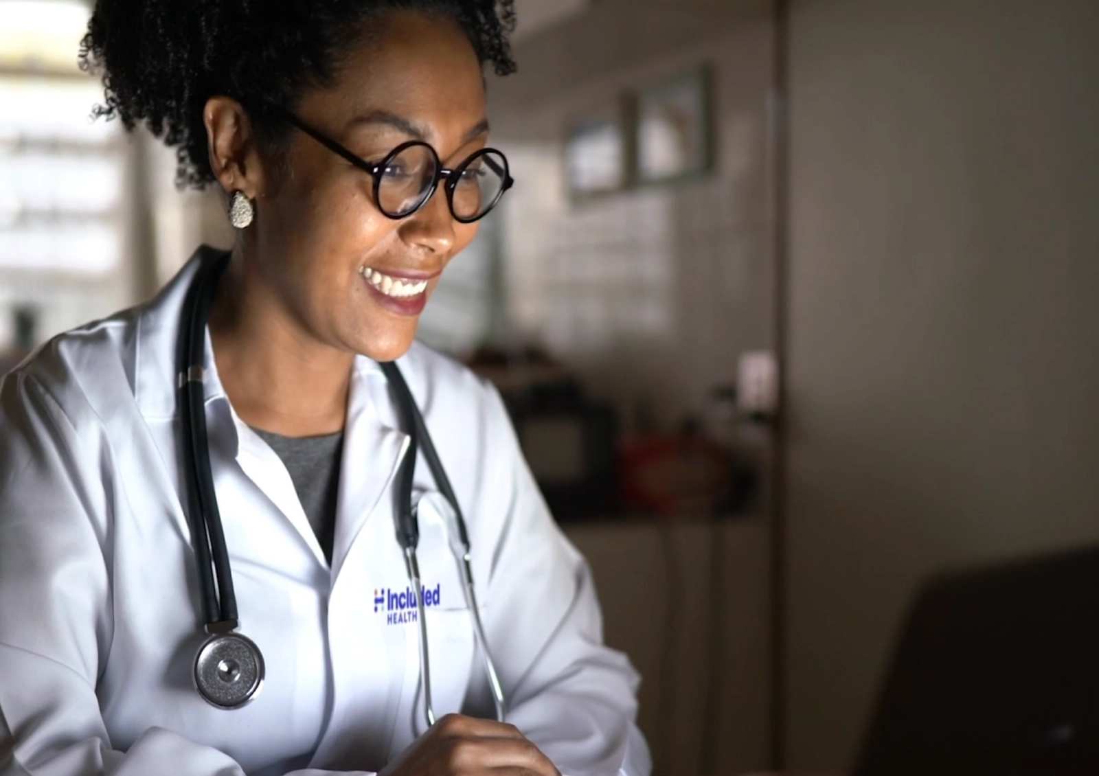 Included Health doctor smiling and talking to her patient on her computer.