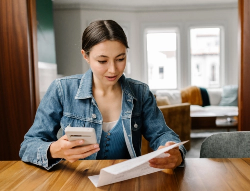 woman with phone on kitchen table looking at paper