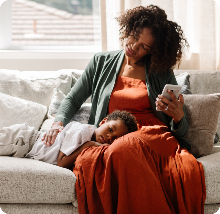 Mamá en el sofá usando la aplicación Incluido Salud para su hijo.