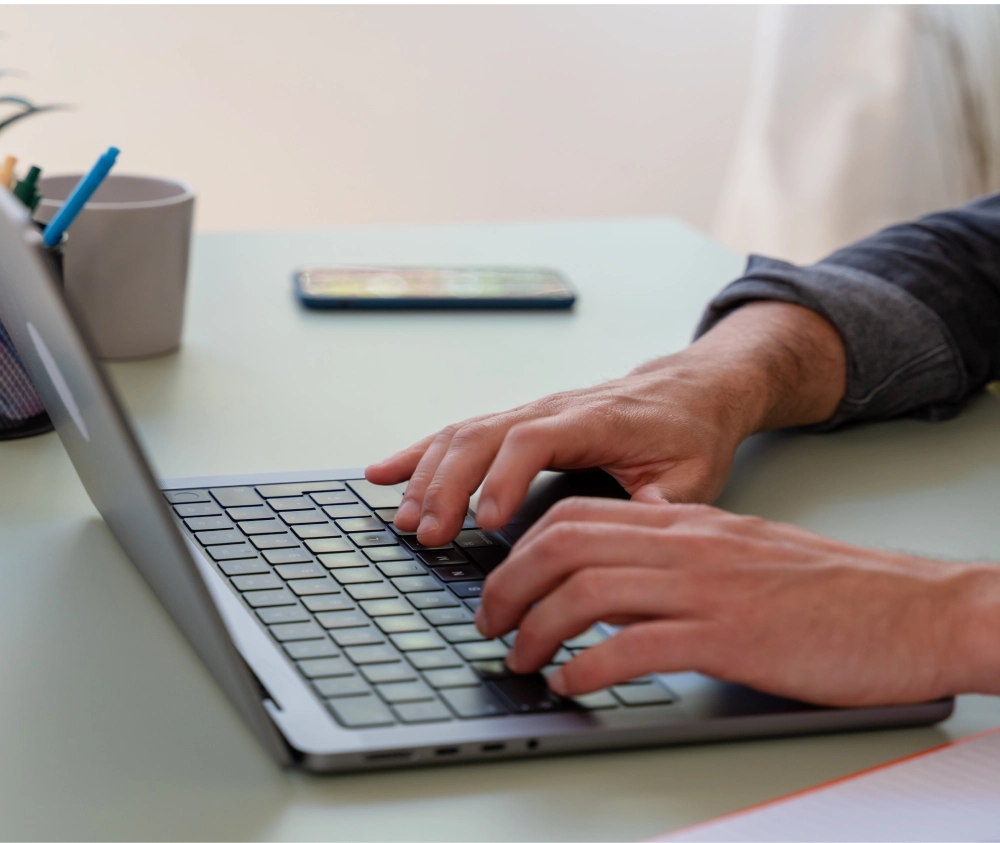 close up image of hands typing on a laptop keyboard.