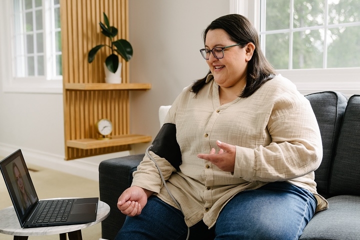 woman taking her own blood pressure at home on telehealth visit