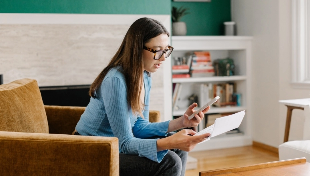 woman sitting on couch navigating her health care bills and claims.
