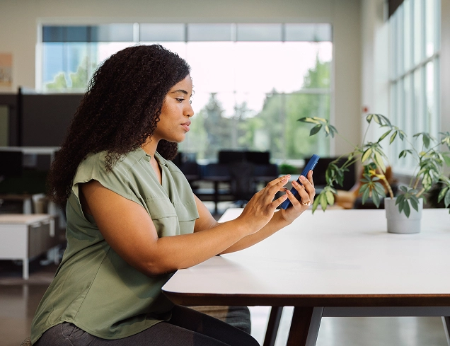 woman sitting at desk using mobile phone