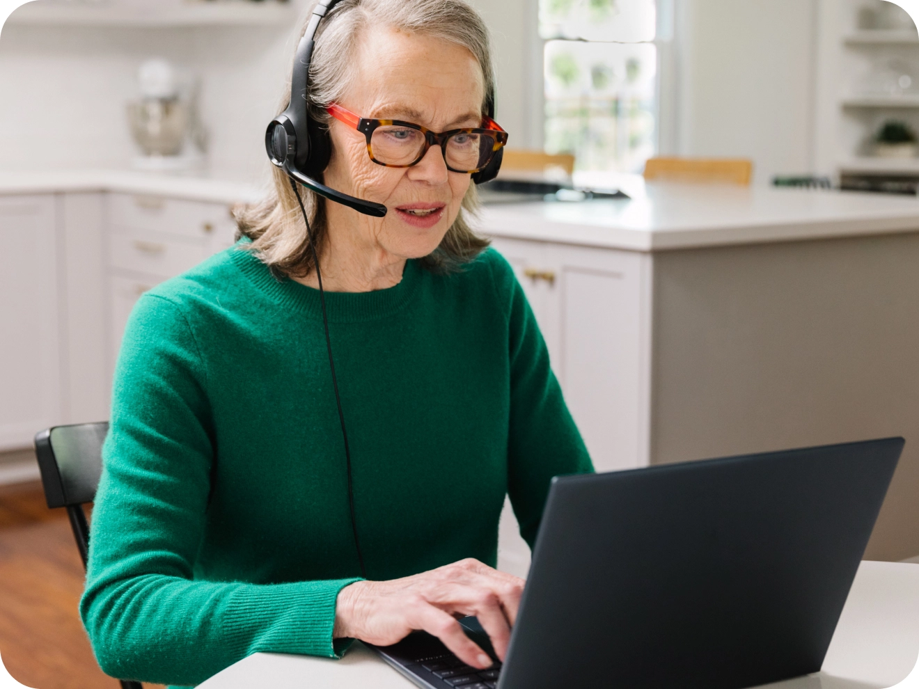 Home care coordinator speaking on the phone while looking at her laptop