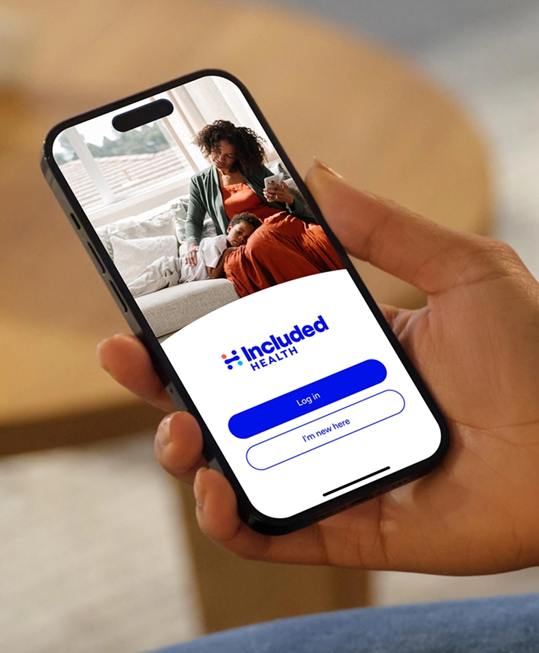 Person holding a mobile phone with the login screen on the Included Health app.