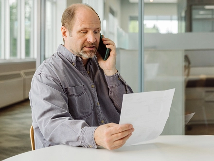 Middle aged man discussing a medical bill with a care advocate at work.