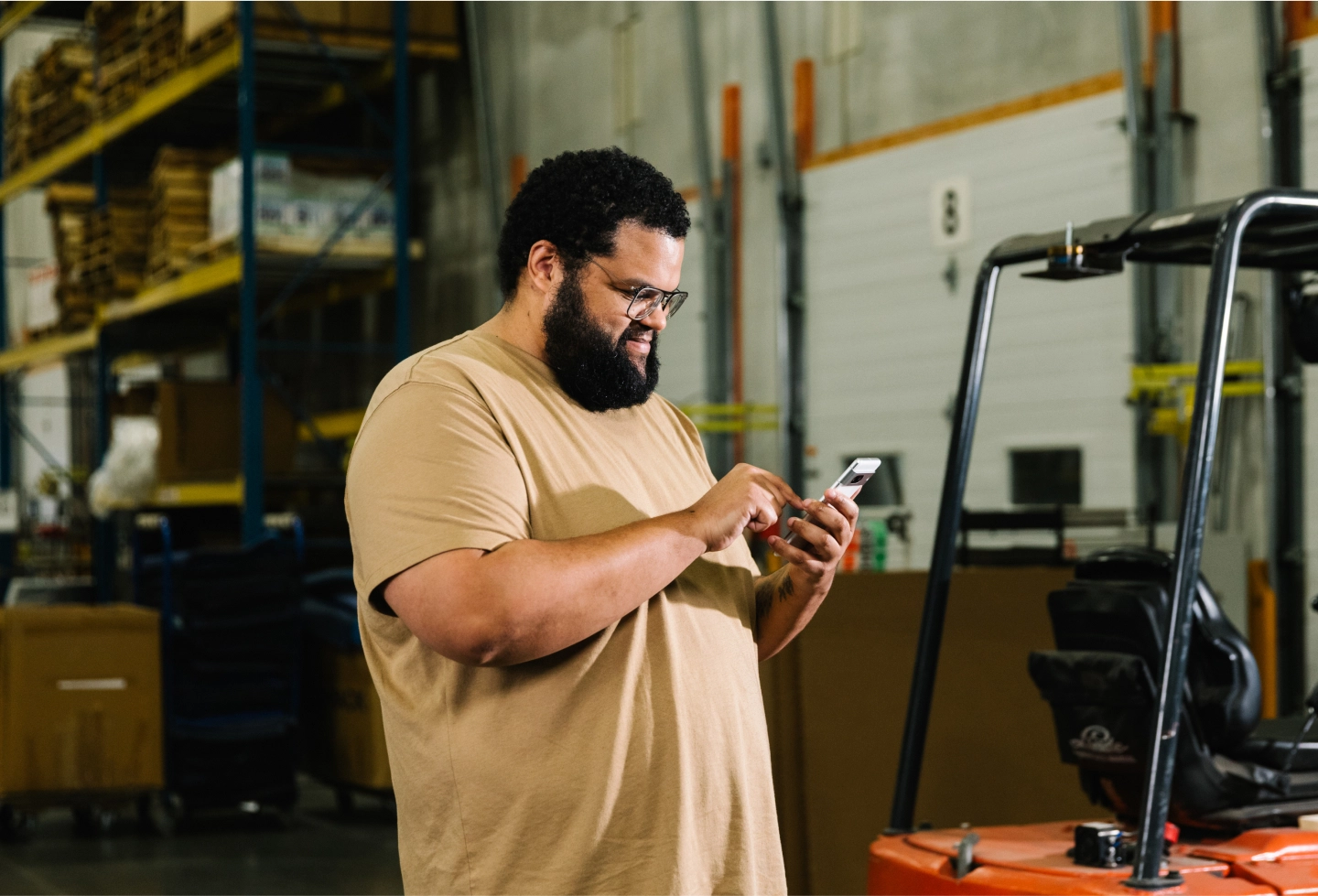 man in front of forklift holding phone