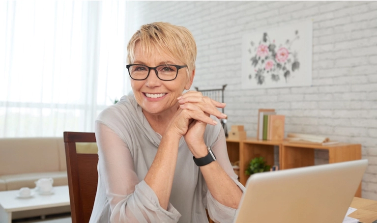 Woman with glasses behind laptop

