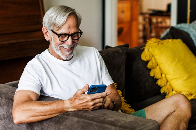 Older man viewing their phone while sitting on a couch