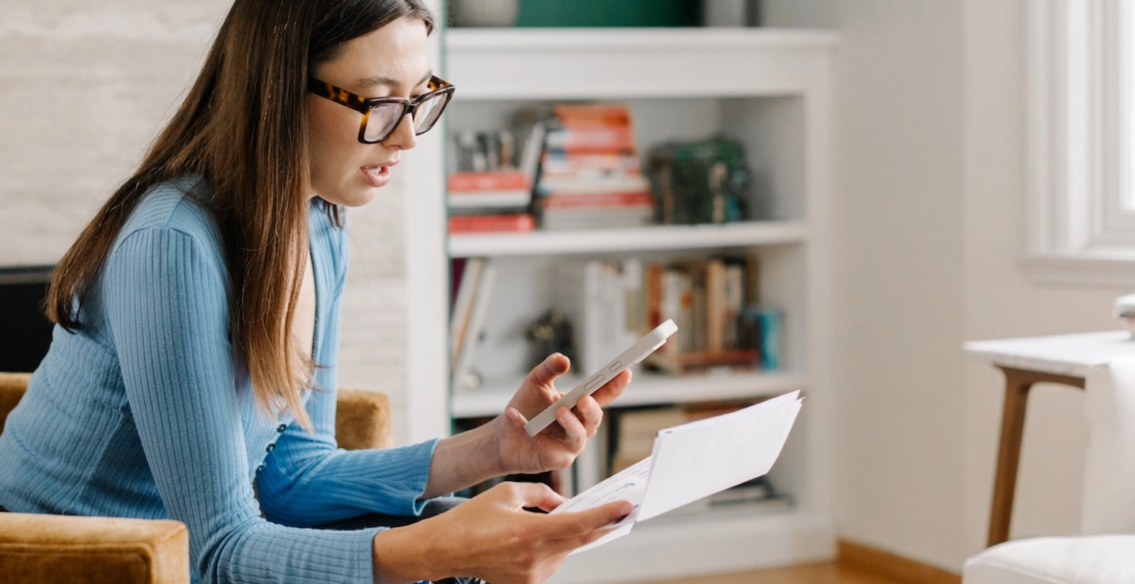 Woman holding phone looking at medical bill