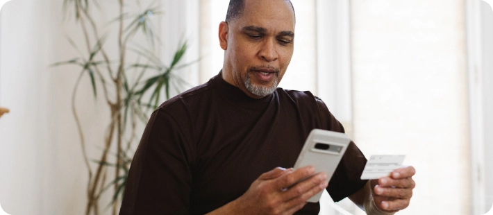 Man looking at his phone and medical insurance card