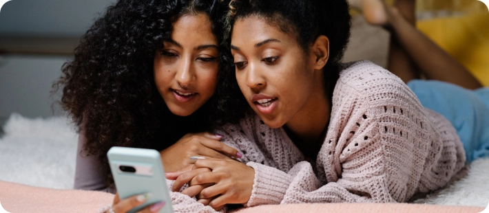 Two girls looking at the Included Health app on a phone