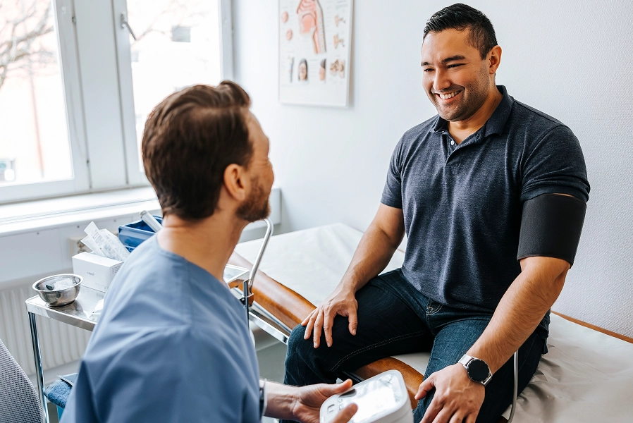 Patient getting blood pressure taken and smiling at doctor in exam room