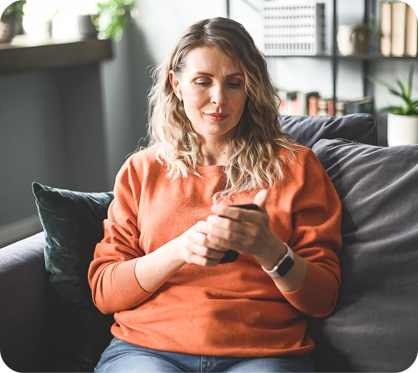 A woman sitting on a couch while looking at her phone.