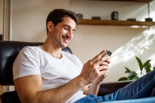 Man smiling while looking at his phone
