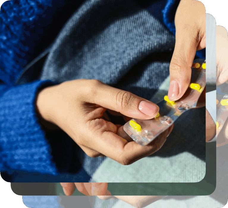 Close-up of a person's hands pushing yellow pills out of a blister package. An overlay shows prescription information for Losartan, 30 day supply, with a note to save $90/month.