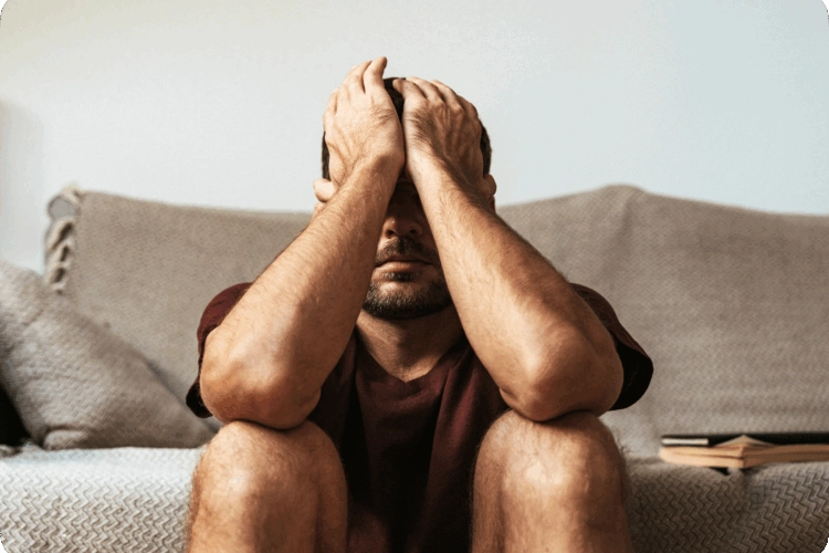 A stressed man sitting on a couch.