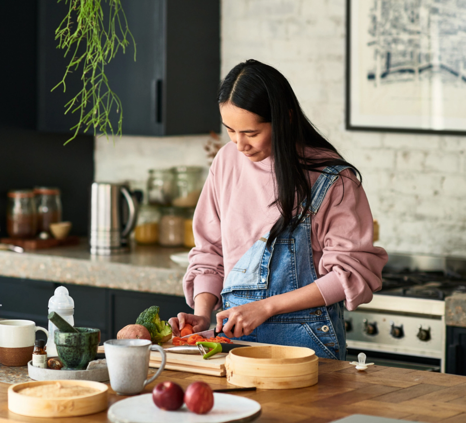 A woman cutting vegetables vegetables in her kitchen.
