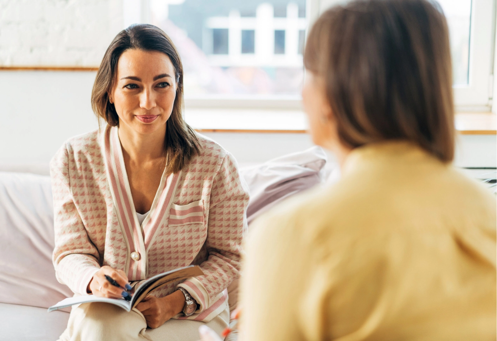 Two women sitting down together and conversing.